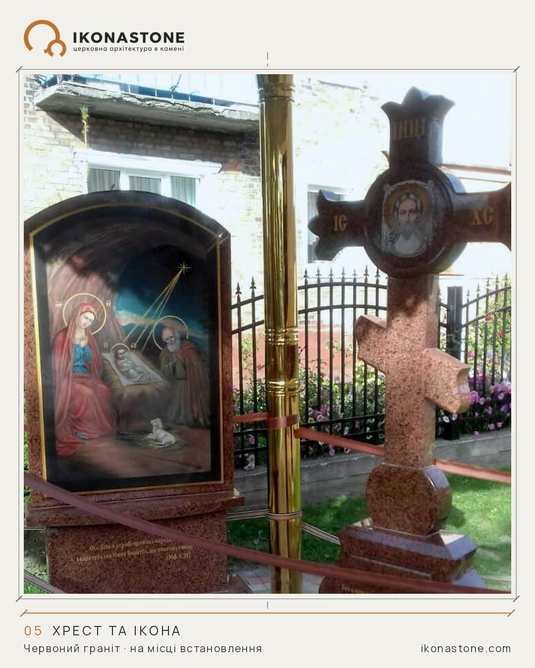 A red granite cross with a round image of Christ, and a dark arched slab with a colour Nativity on a granite base, with a fence and flowers nearby